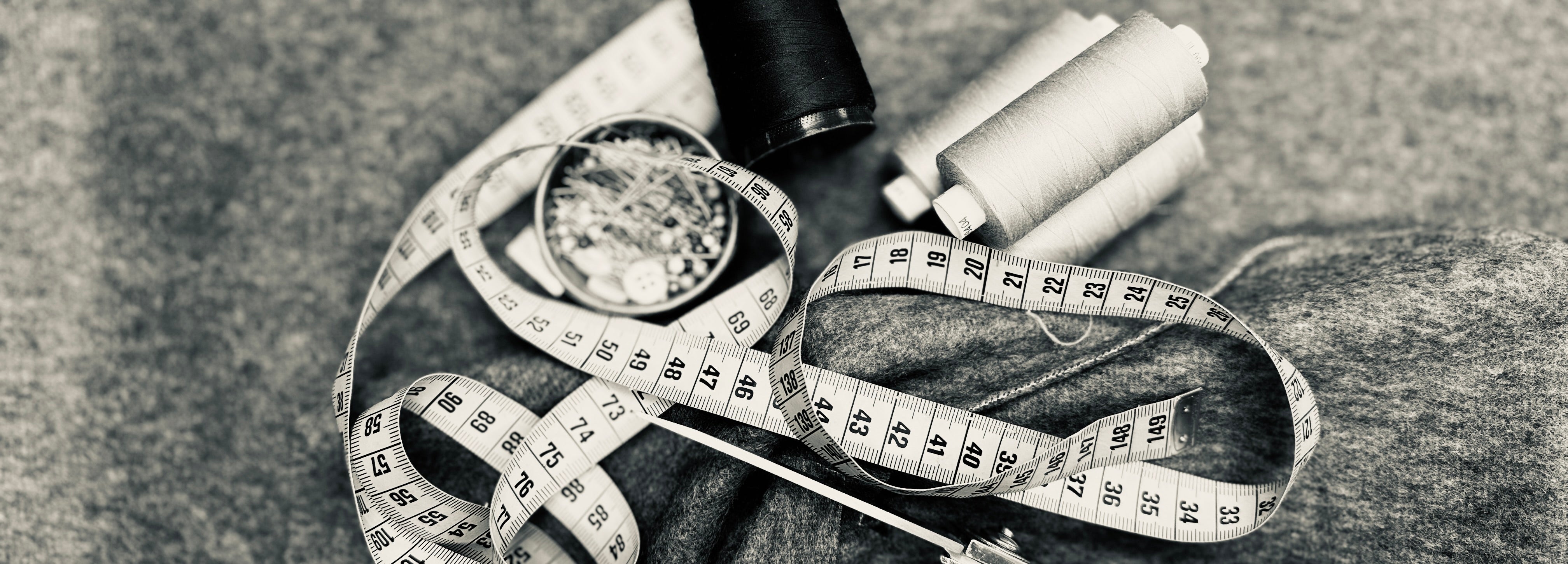 Maßband, Garnrollen und Nähzubehör als Symbol für die handgefertigte Couture und die sorgfältige Verarbeitung bei DEFONDO.