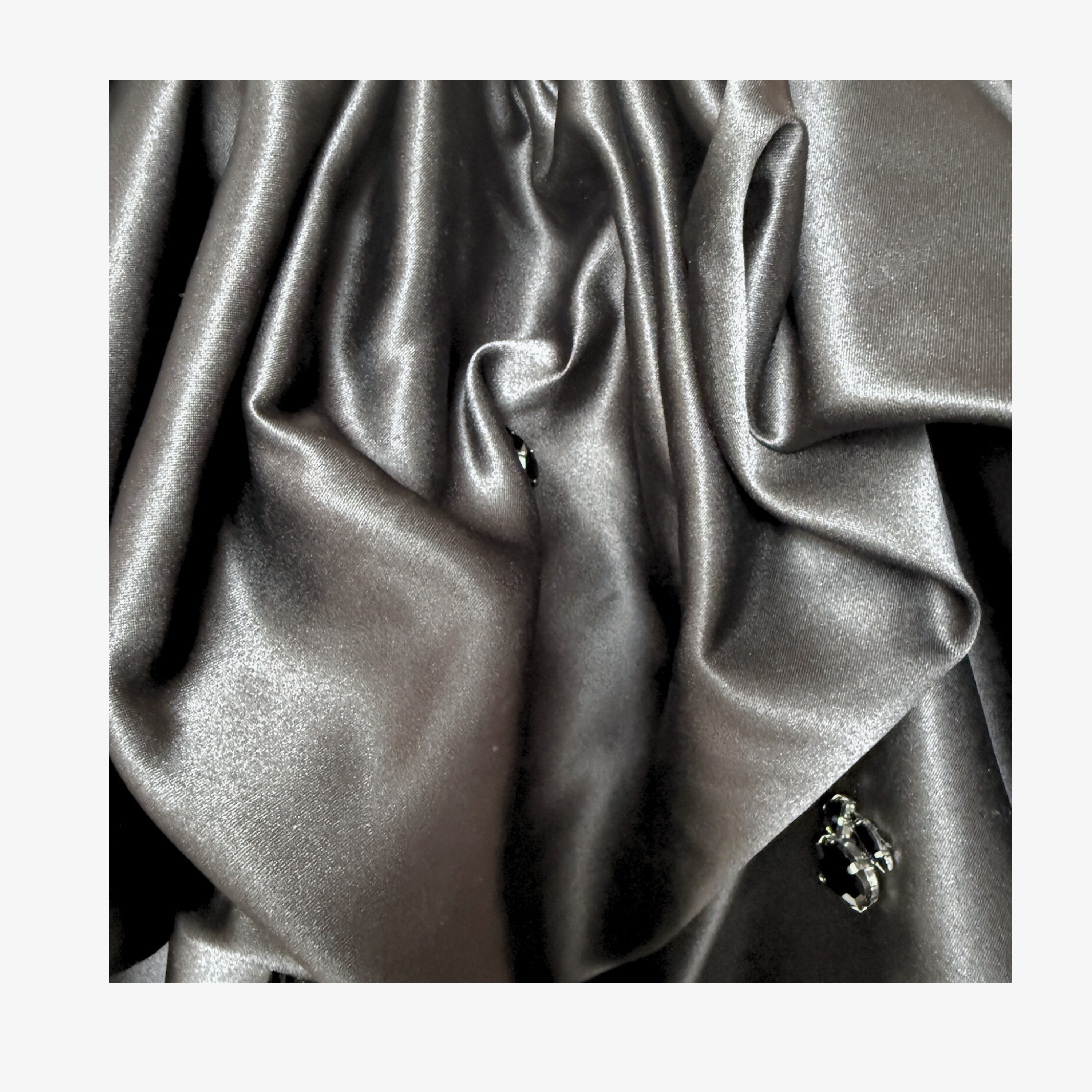 Detailaufnahme des schwarzen Satinstoffs mit eleganten Falten und hochwertiger Verarbeitung.