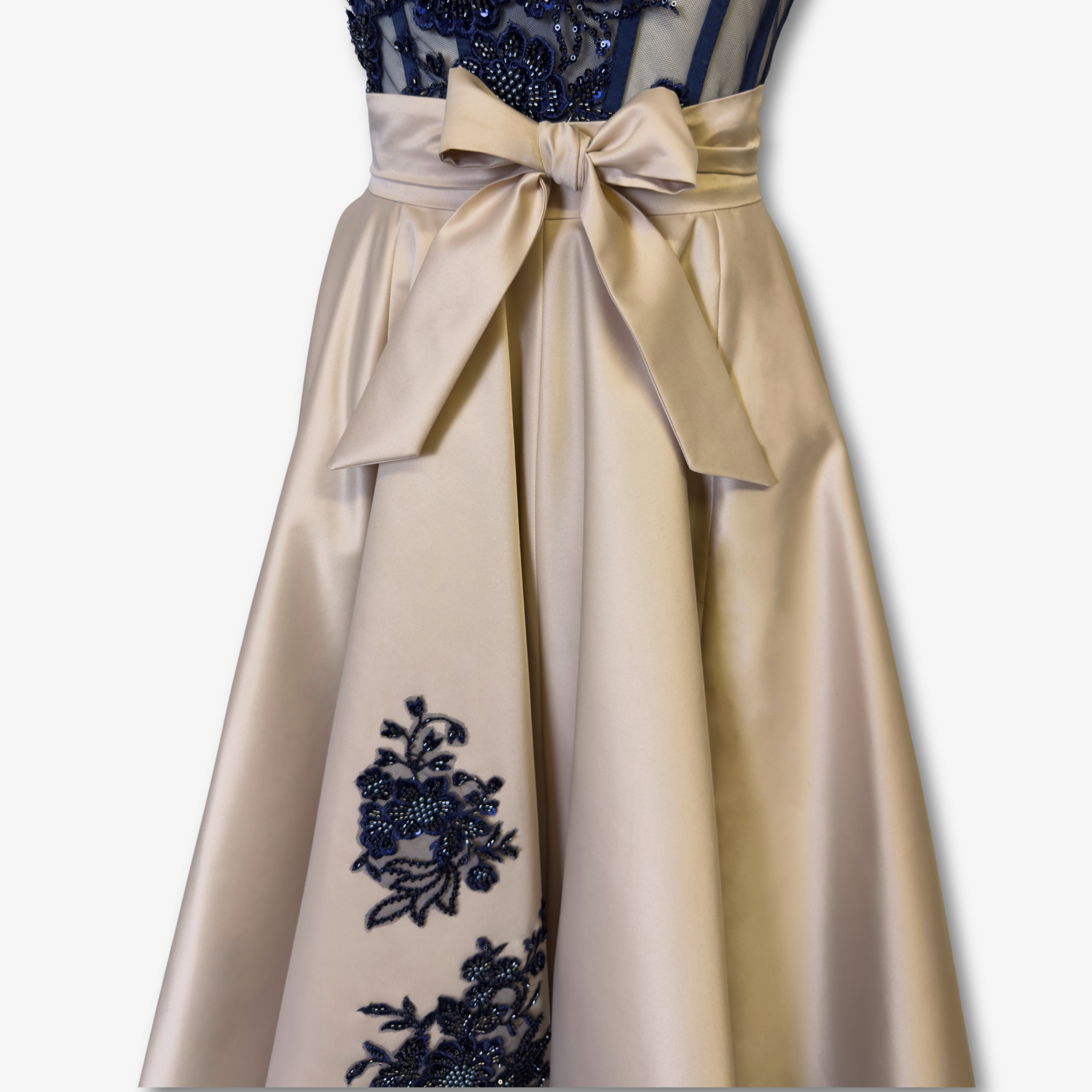 Detailaufnahme der blauen Perlenstickerei auf champagnerfarbenem Taft des asymmetrischen Tellerrocks von DEFONDO.
